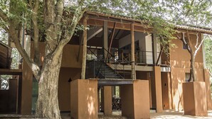 A building with a covered outdoor area, a staircase, and a tree in front. - Wapi Bungalowi Yala (Thissamaharama)