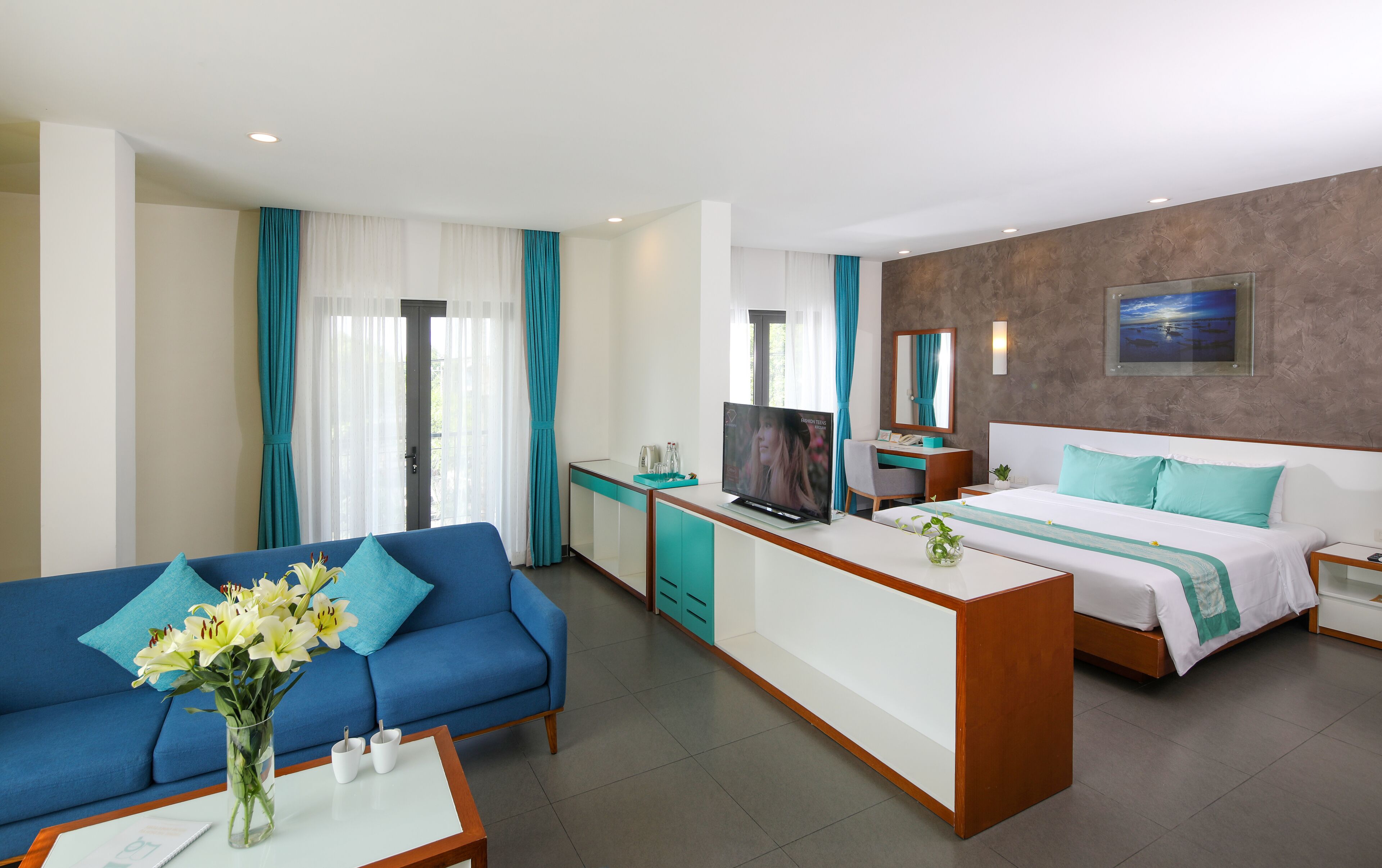 A hotel room with a sofa, a bed, a desk, and a TV.