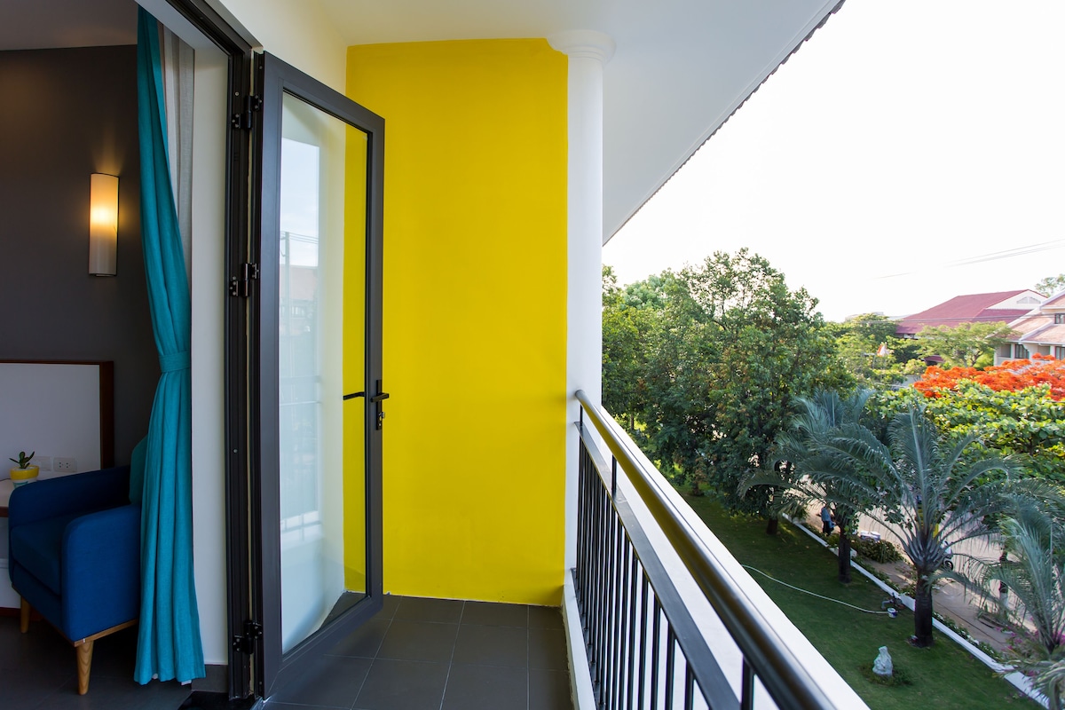 A balcony with a yellow wall, a blue chair, and a glass door.