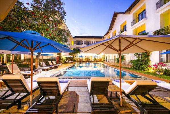 Una piscina al aire libre, sombrillas, sillones reclinables de piscina