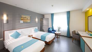 A hotel room with two beds, a desk, a chair, a small table, and a window with curtains.