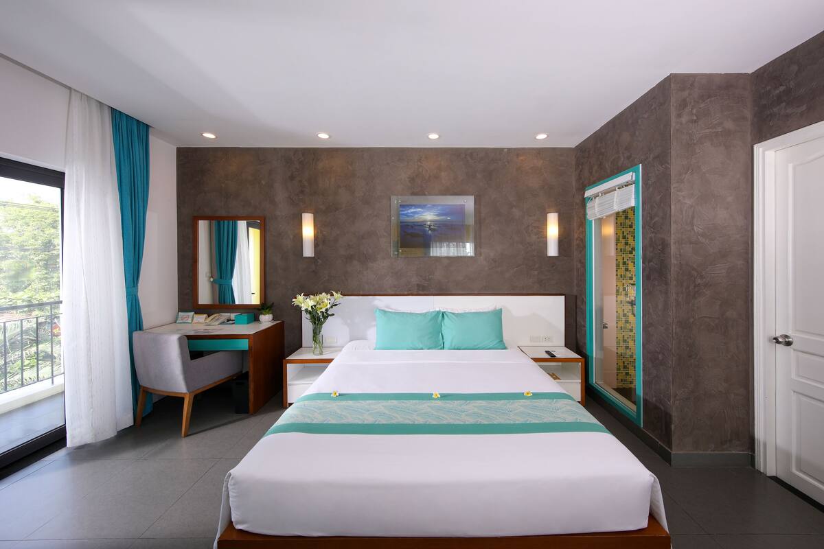 A modern hotel room with a large bed, a desk, and a bathroom with a glass shower.