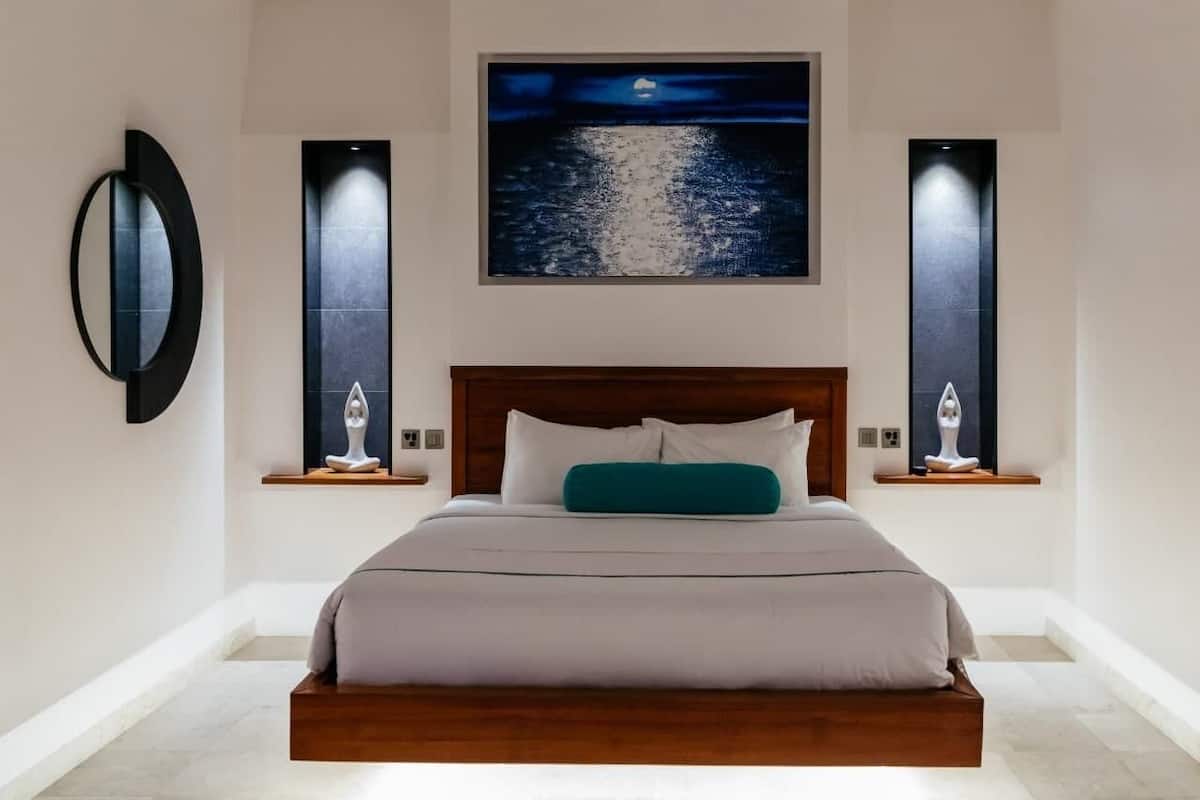 A modern bedroom with a large bed, a night sky painting, and two wall-mounted light fixtures.