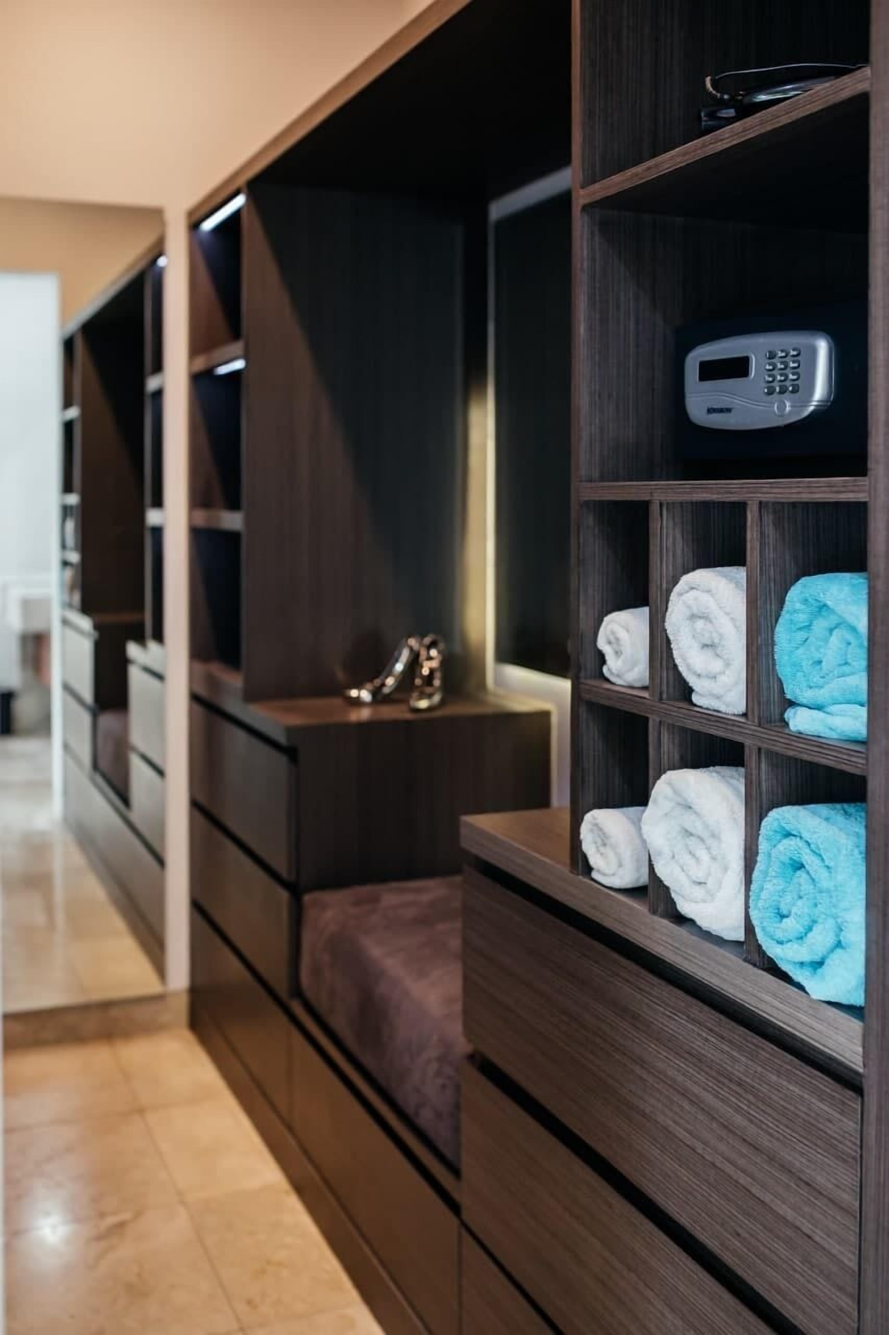 A modern bathroom with a built-in vanity, a towel rack with neatly folded towels, and a digital scale on the vanity.