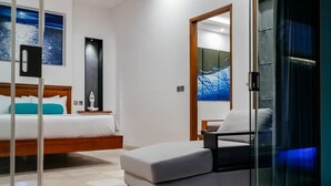 A modern hotel room with a bed, a sofa, a glass partition, and artwork on the walls. - Kamil Villas (Seminyak)