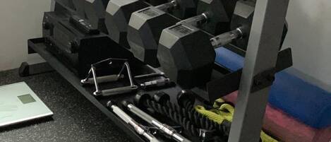 A weightlifting rack with multiple dumbbells and a scale.