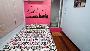 A bedroom with a bed, a pink wall with a city skyline mural, a door, and a window. - Eat - Ting Cafe and Hostel (Bangkok)