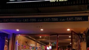 A restaurant with a sign reading "eat Ting Cafe & Hostel" and a festive banner. - Eat - Ting Cafe and Hostel (Bangkok)
