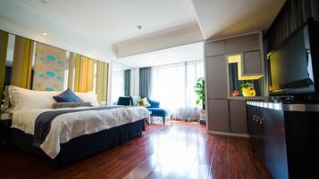 A modern hotel room with a large bed, a TV, a desk, and a view of the outdoors.