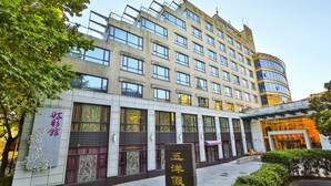 A multi-story hotel with a modern facade, large windows, and a prominent entrance with a covered walkway.