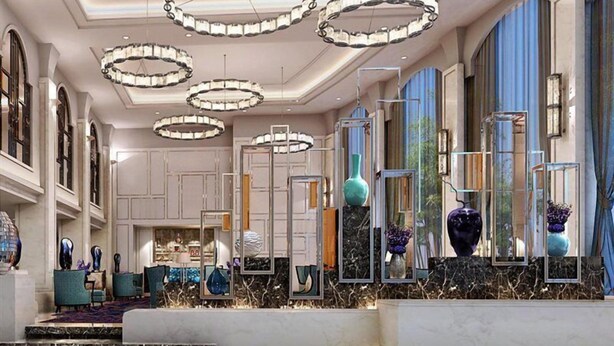 A lobby with marble flooring, multiple chandeliers, and a display of vases.