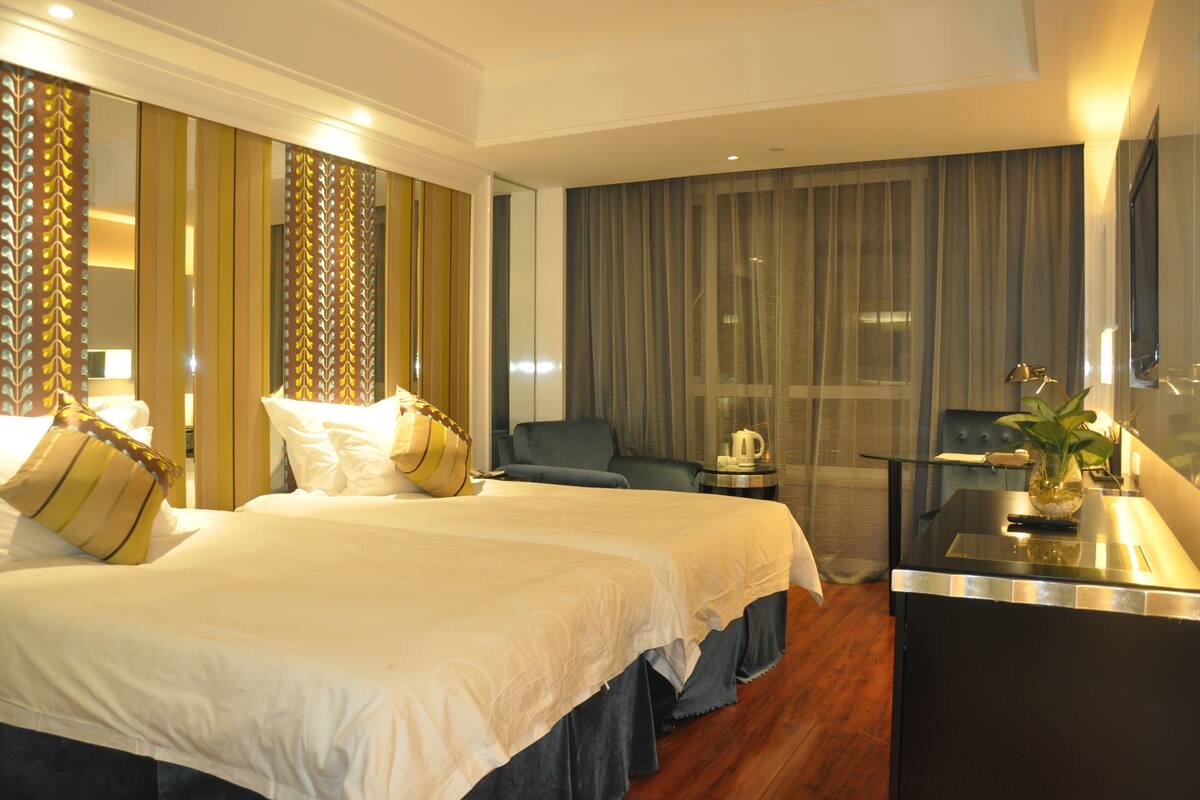 Una habitación de hotel con una cama grande, un escritorio con hervidor y una silla.