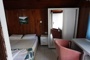 A room with a bed, a desk, a chair, and a small cabinet.