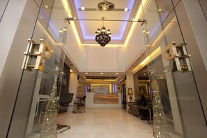 A modern hotel reception area with a glass partition, a chandelier, and a reception desk. - Prestige Suites Nana (Bangkok)