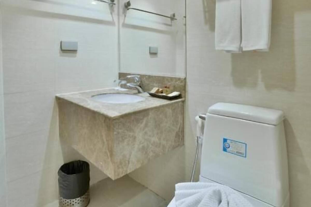 Un baño moderno con lavamanos, espejo, inodoro y toallero.