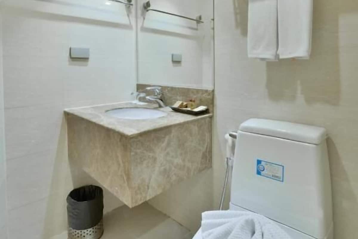A modern bathroom with a sink, mirror, toilet, and towel rack.