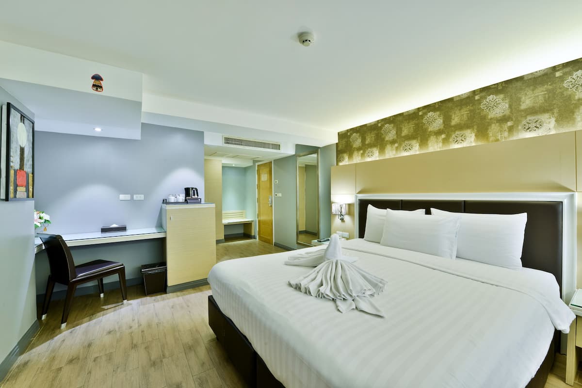 Una habitación de hotel con una cama grande, un escritorio, una silla y una pequeña cocina americana.