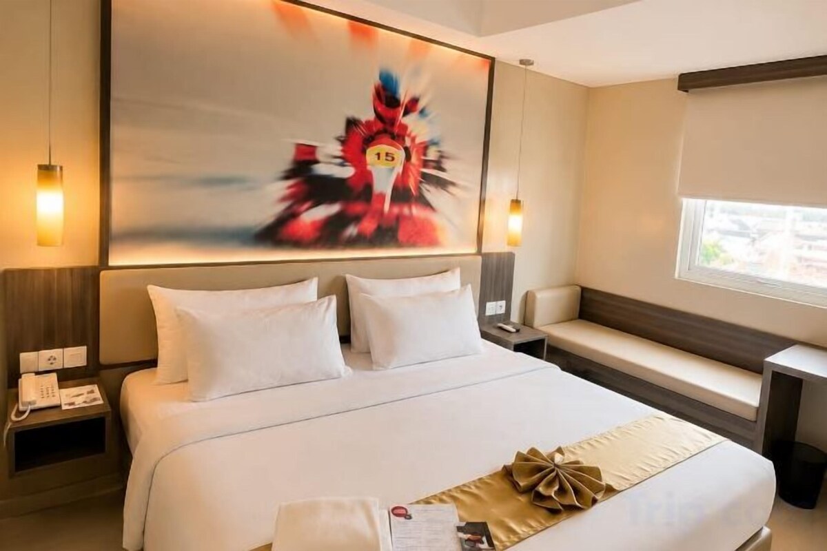 Habitación de hotel con una cama grande, mesitas de noche, una ventana y un cuadro en la pared.