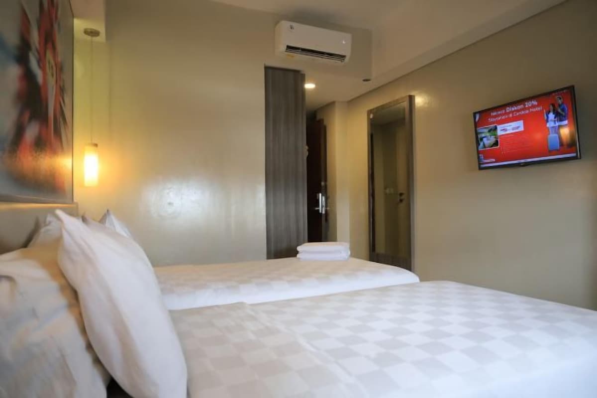 Una habitación de hotel con una cama, televisión y aire acondicionado.