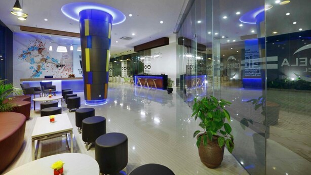 A modern lobby with a reception desk, seating area, and a large pillar with blue lighting. - Cordela Kartika Dewi Jogjakarta (Yogyakarta)