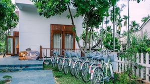 A row of bicycles parked outside a building with a white facade, wooden doors, and a white picket fence. - New Sunshine Homestay (Da Nang)