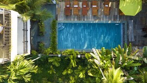 A rectangular swimming pool surrounded by wooden deck chairs and a wooden fence. - New Sunshine Homestay (Da Nang)