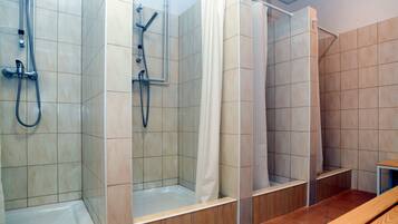 Zona de ducha con paredes de azulejos, un banco y un cabezal de ducha.