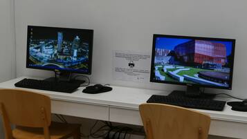 Two computer monitors on a desk with a keyboard and mouse, a chair, and a sign with text.