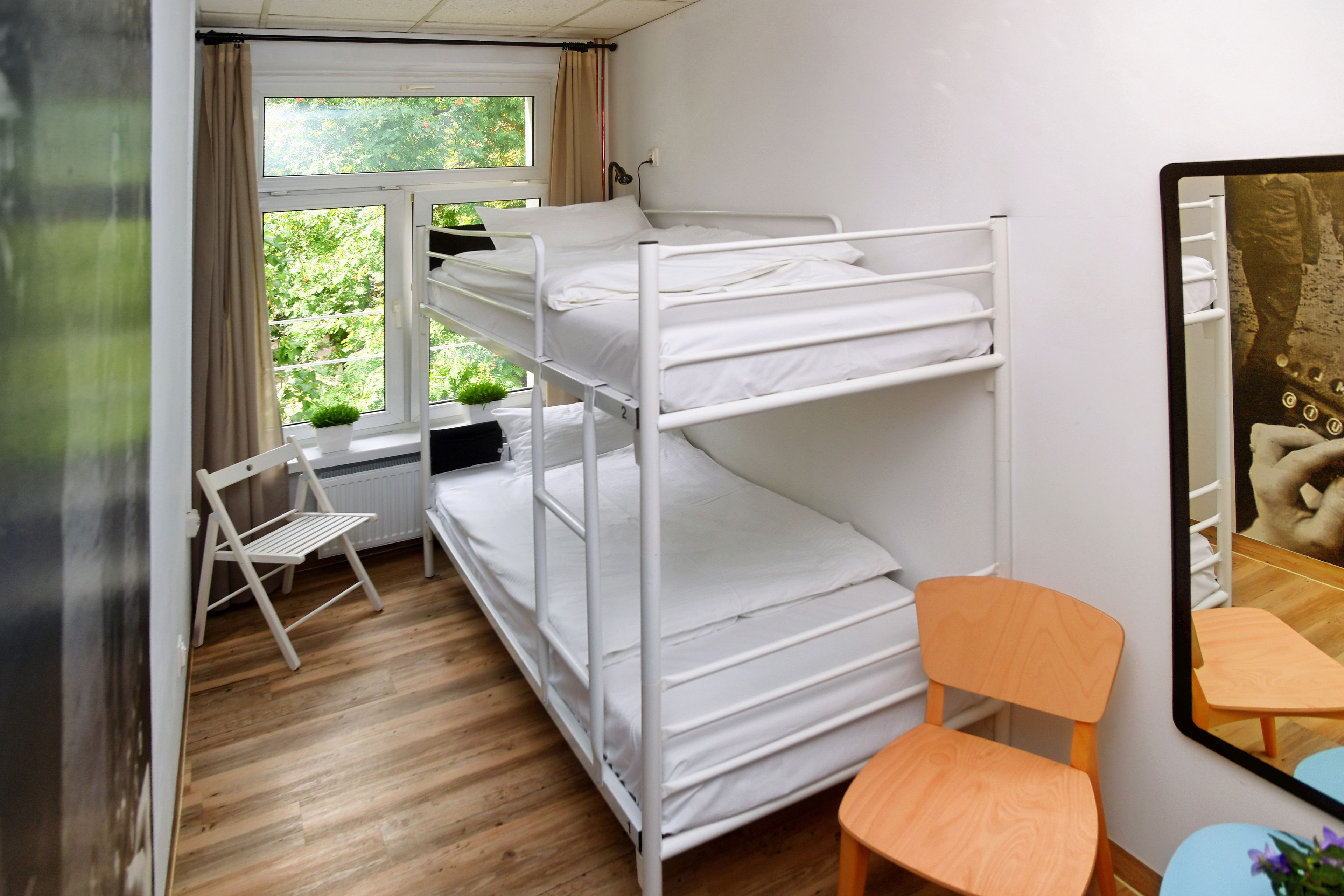 A bunk bed room with a desk, chair, and a window with curtains.