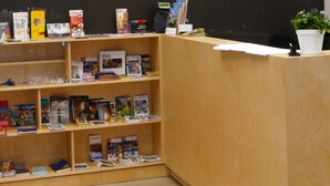 Una recepción con un mural de la ciudad, estantes de madera con libros y lámparas colgantes.