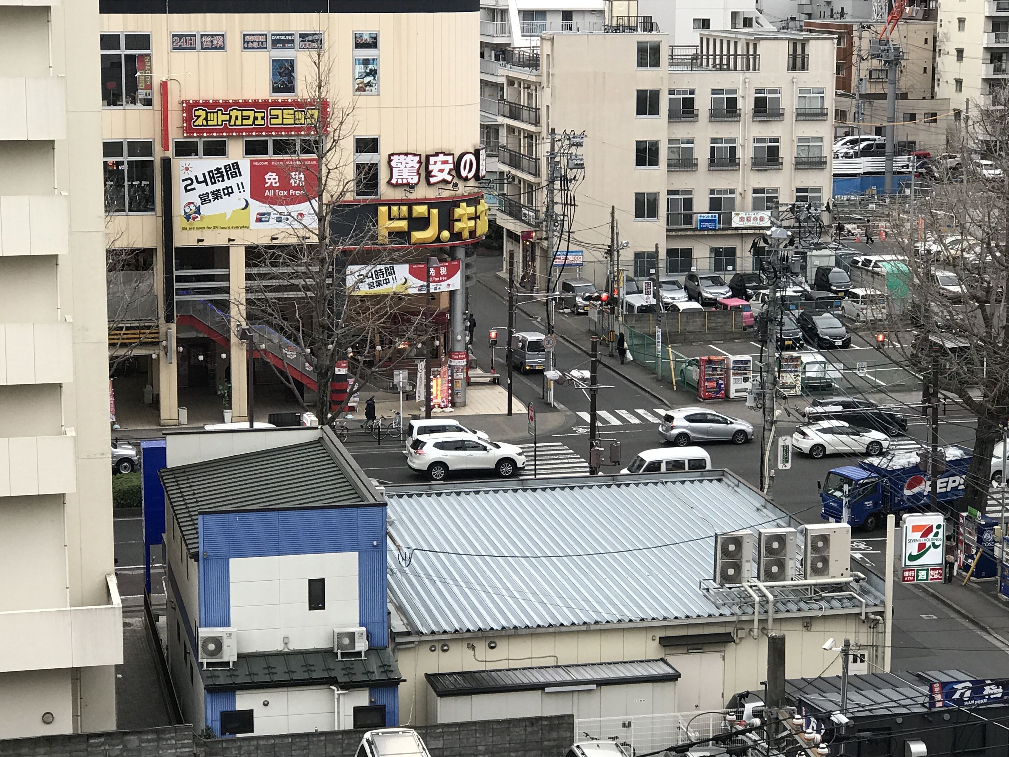 A busy urban street with commercial buildings, vehicles, and pedestrians.