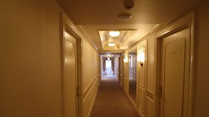 Un couloir d'hôtel avec des revêtements de sol en moquette, des murs de couleur crème et des portes de chaque côté.
