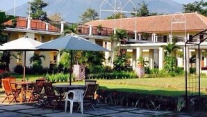 A hotel with outdoor seating, a view of a volcano, and a clear sky. - d'Emmerick Salib Putih Hotel Salatiga (Salatiga)