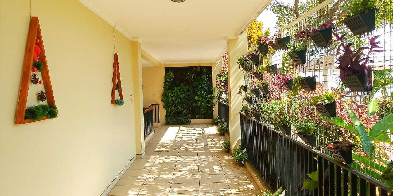 A corridor with a tiled floor, a wooden ladder decoration on the wall, and a metal fence with hanging planters.