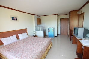 Een hotelkamer met een groot bed, een televisie, een koelkast en een houten garderobe.