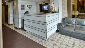 A reception area with a modern design, featuring a reception desk, a sofa, and a chandelier. - The Prestige Nana (Bangkok)