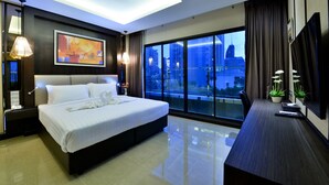 A modern hotel room with a large bed, a desk, and a city view through floor-to-ceiling windows. - The Prestige Nana (Bangkok)