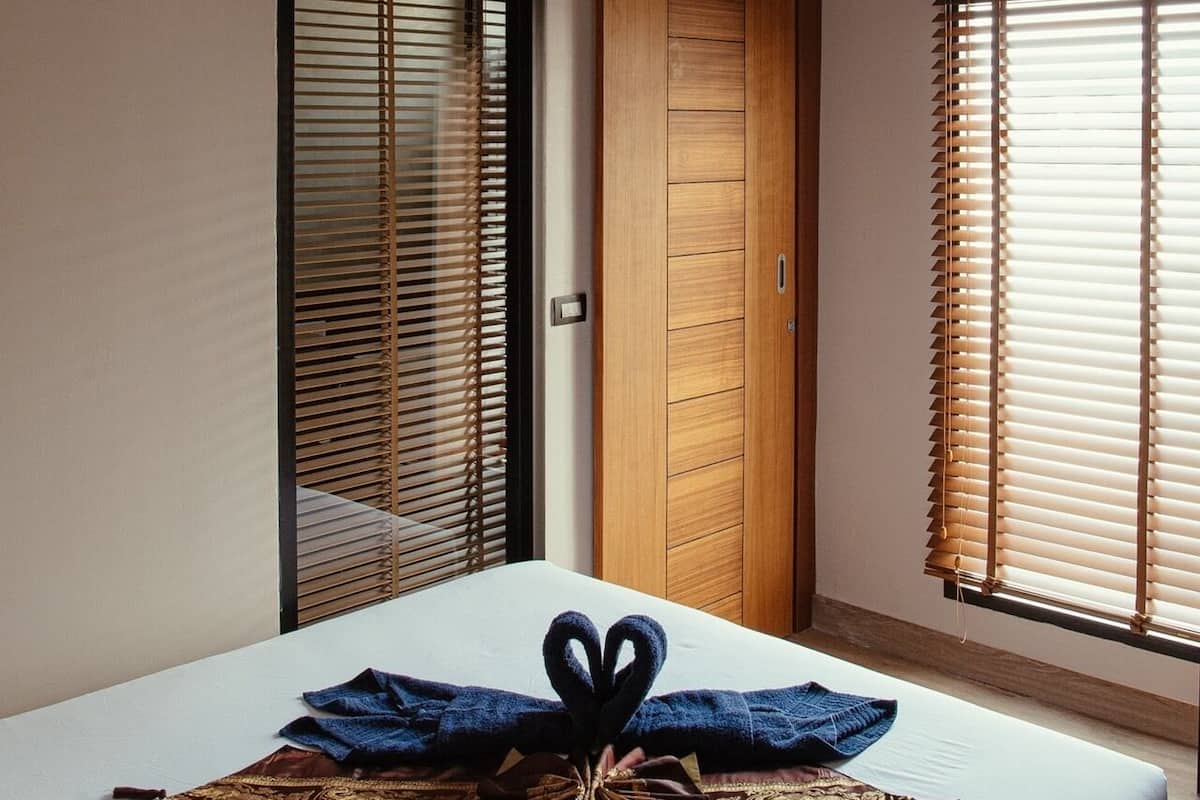 Quarto com cama, guarda-roupa de madeira e janela com persianas.