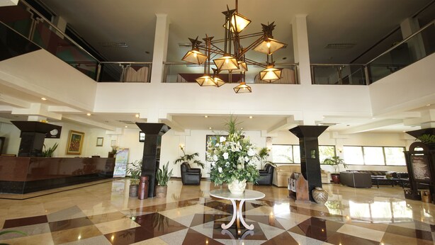 A spacious lobby with a checkered floor, a reception desk, seating areas, and a decorative chandelier. - Bahari Inn Tegal (Tegal)