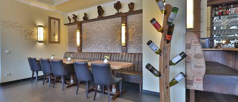 Un restaurante con pared de piedra, bancos de madera y una estantería para botellas de vino.