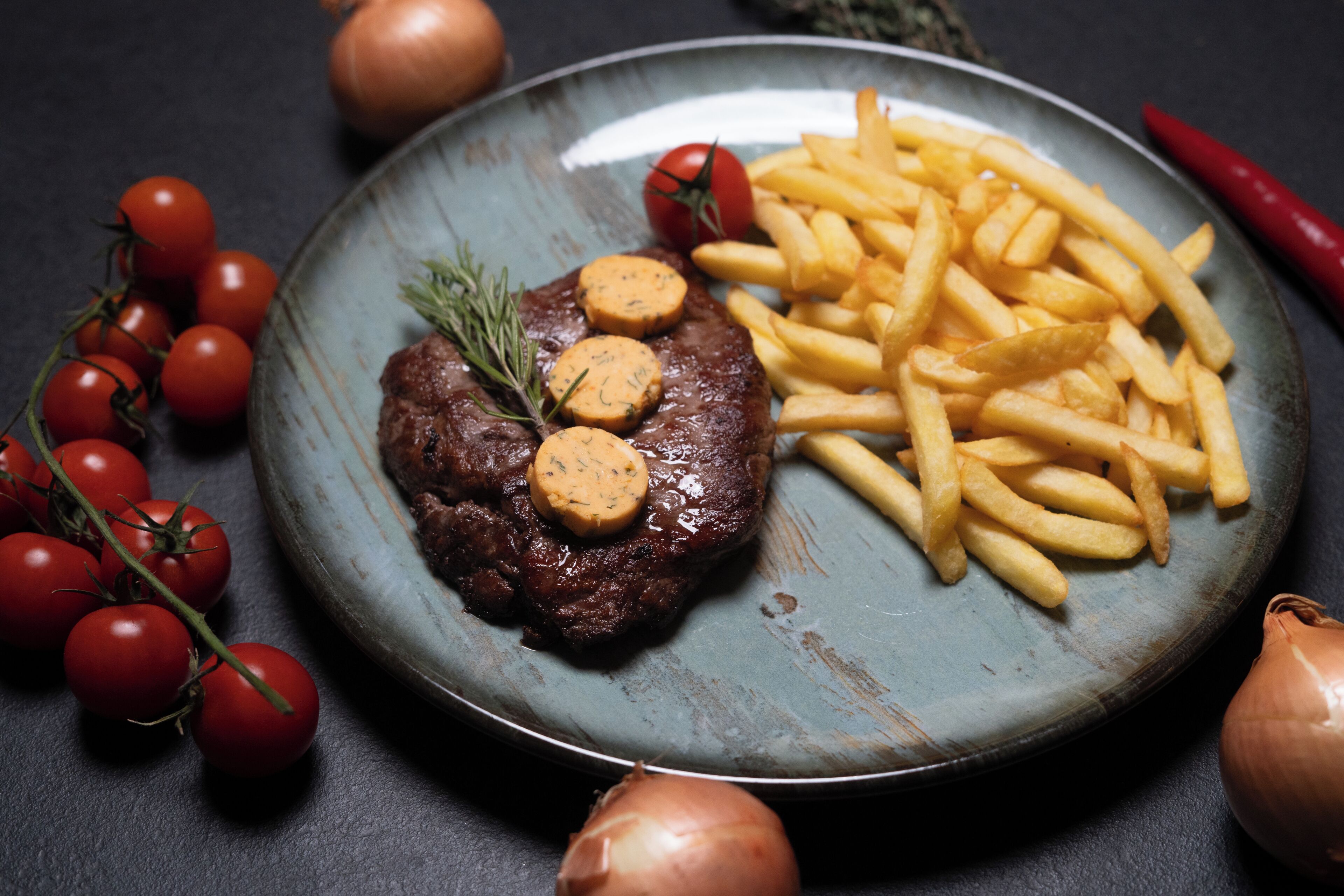 A plate with steak, fries, and cherry tomatoes.