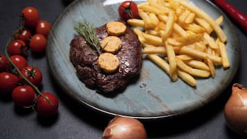 Een bord met steak, friet en cherrytomaten.