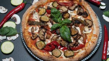 A pizza with various toppings and vegetables on a metal tray.