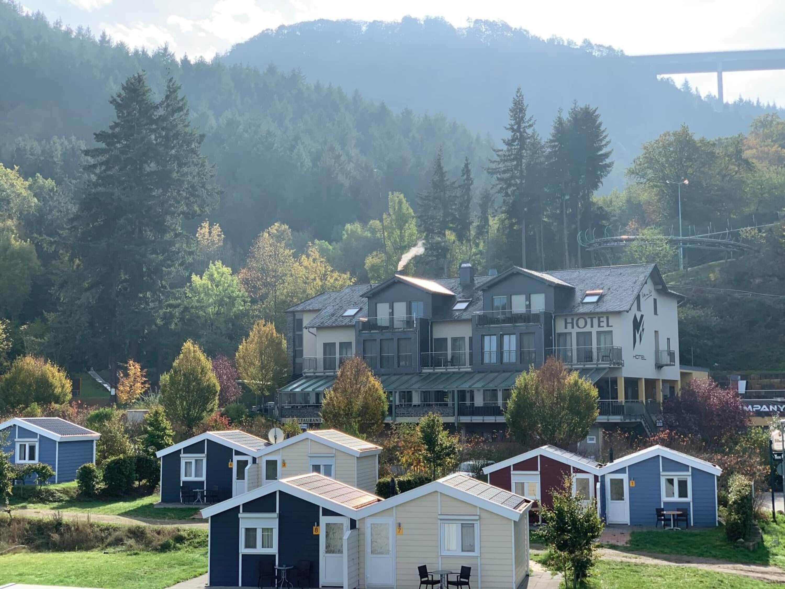 Un hotel con varias construcciones, incluyendo un llamativo letrero que dice 'HOTEL'. Se observan varias cabañas más pequeñas en primer plano.