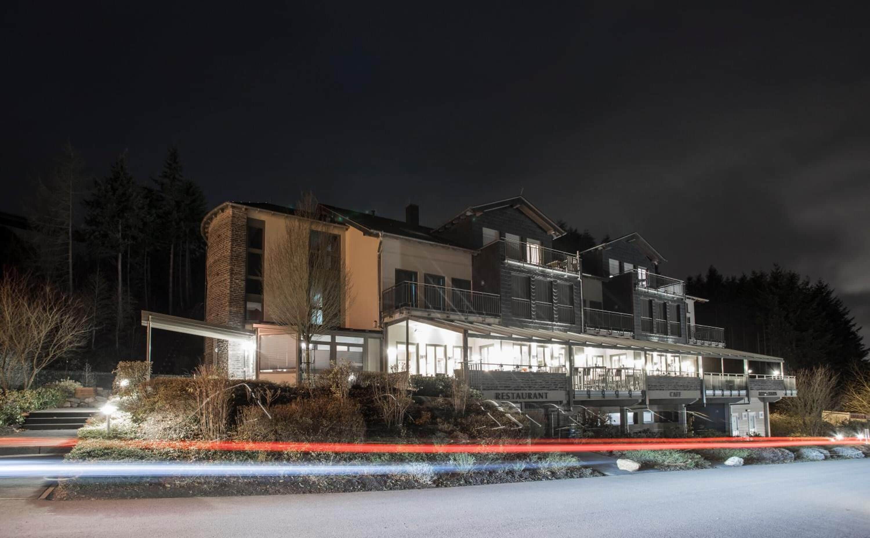 A multi-story building with a restaurant and cafe on the ground floor, surrounded by trees.