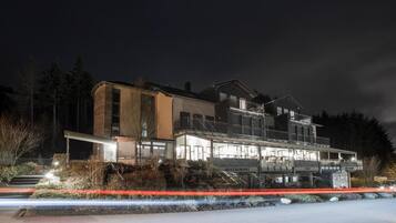 A multi-story building with a restaurant and cafe on the ground floor, surrounded by trees.