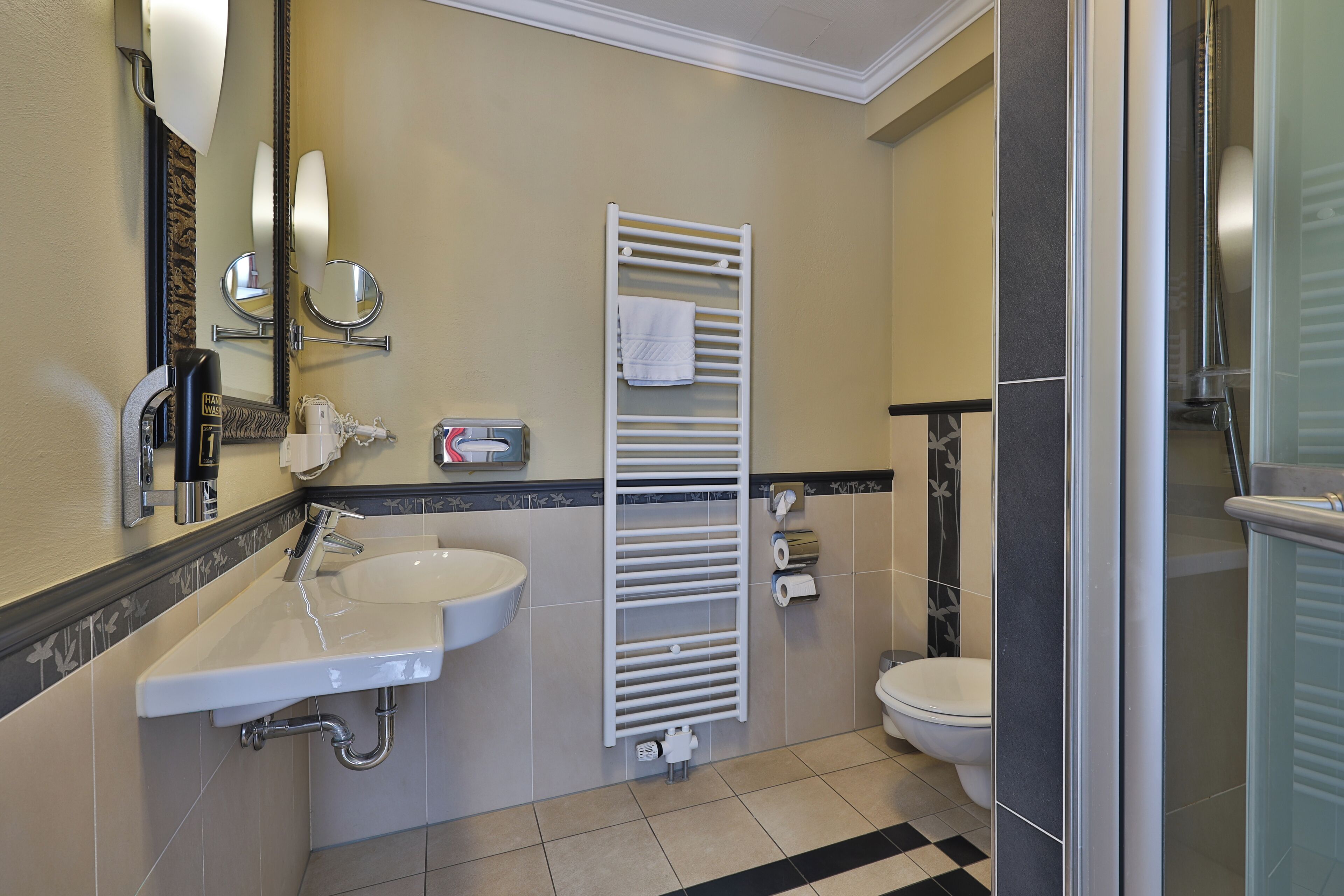 A bathroom with a sink, mirror, towel rack, toilet, and shower area.