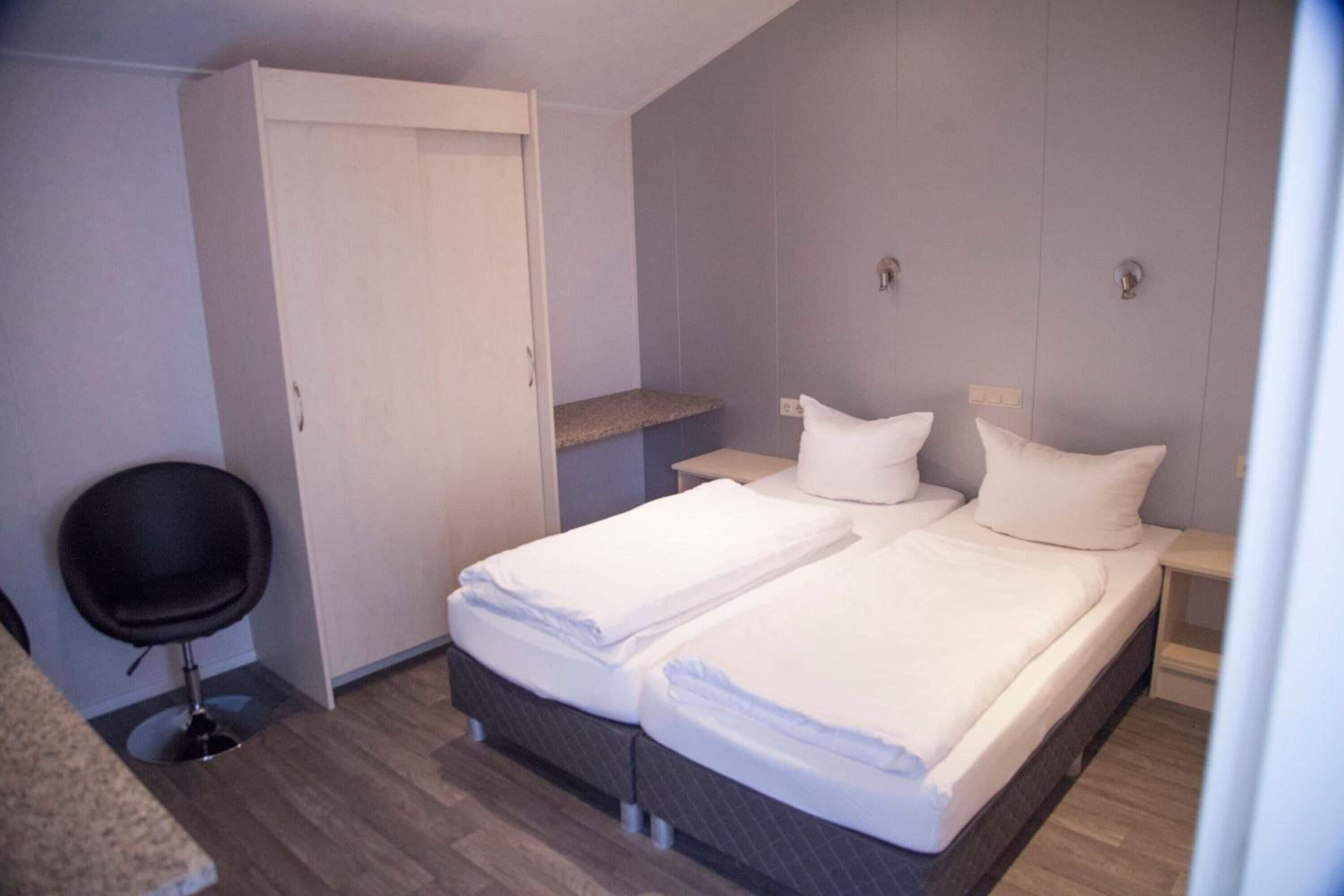 Een hotelkamer met twee bedden, een bureau, een stoel en een kledingkast.