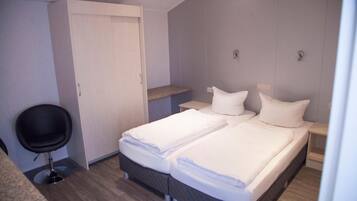 Een hotelkamer met twee bedden, een bureau, een stoel en een kledingkast.