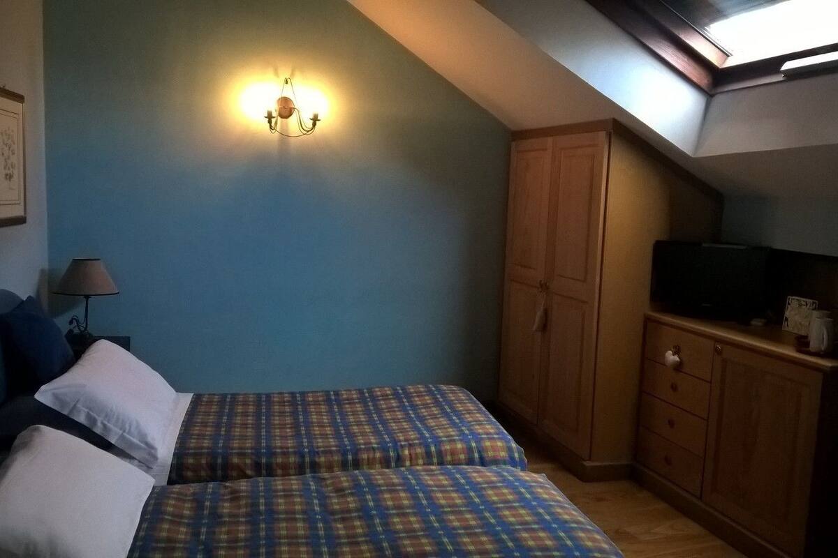 Ein Schlafzimmer mit zwei Betten, einem Kleiderschrank, einem Fernseher und einem Oberlicht.